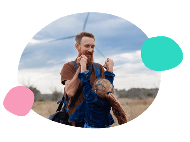 father and daughter playing in front of a wind turbine