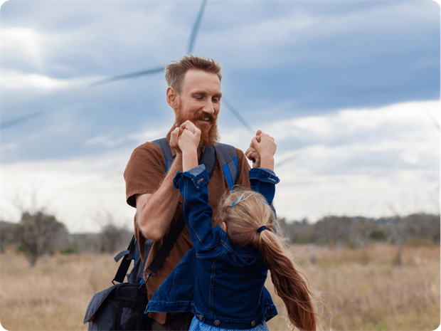 father and daughter playing in front of a wind turbine