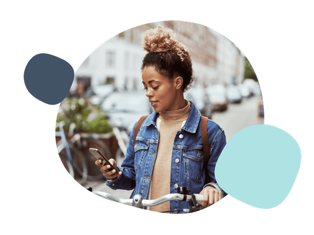 Young woman using her mobile whilst holding her bike