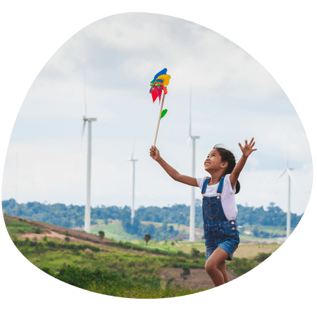 young girl chasing a kite by wind turbines