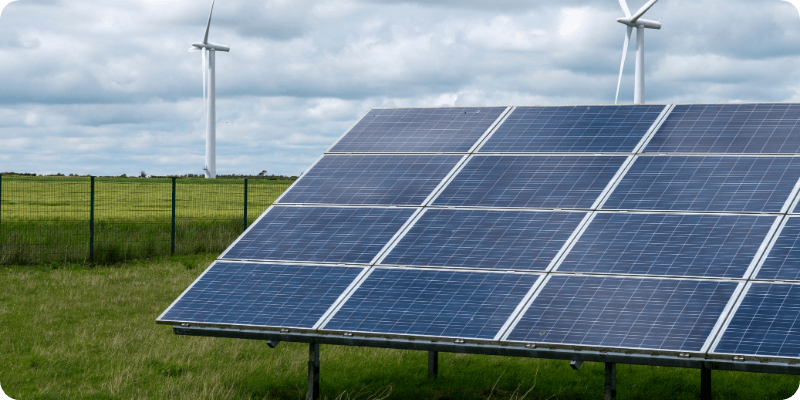 solar panels with wind turbines in the background