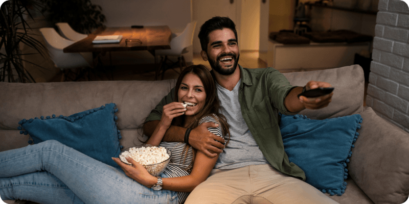 young couple sat watching the TV together