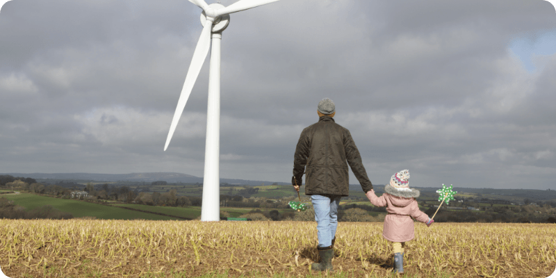 father and daughter holding hands infront of a wind turbine