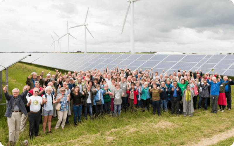 energy project group stood infront of solar panels and wind turbines