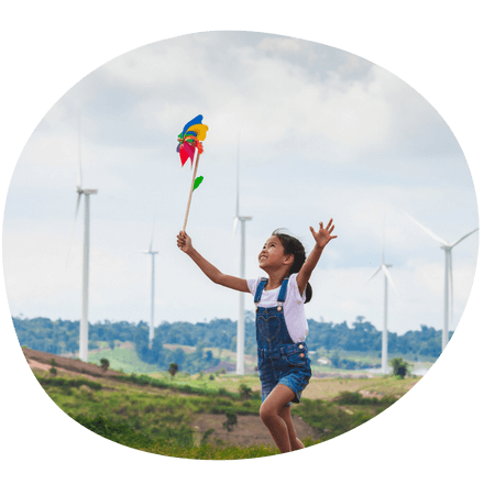 young girl playing with a kite near wind turbines