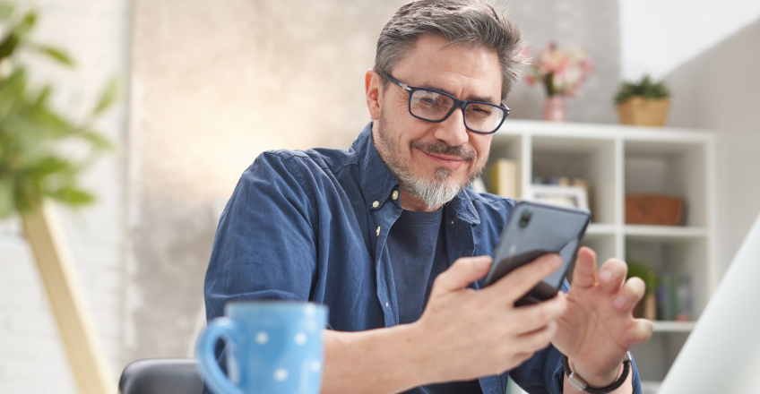 Man using his mobile whilst enjoying a coffee